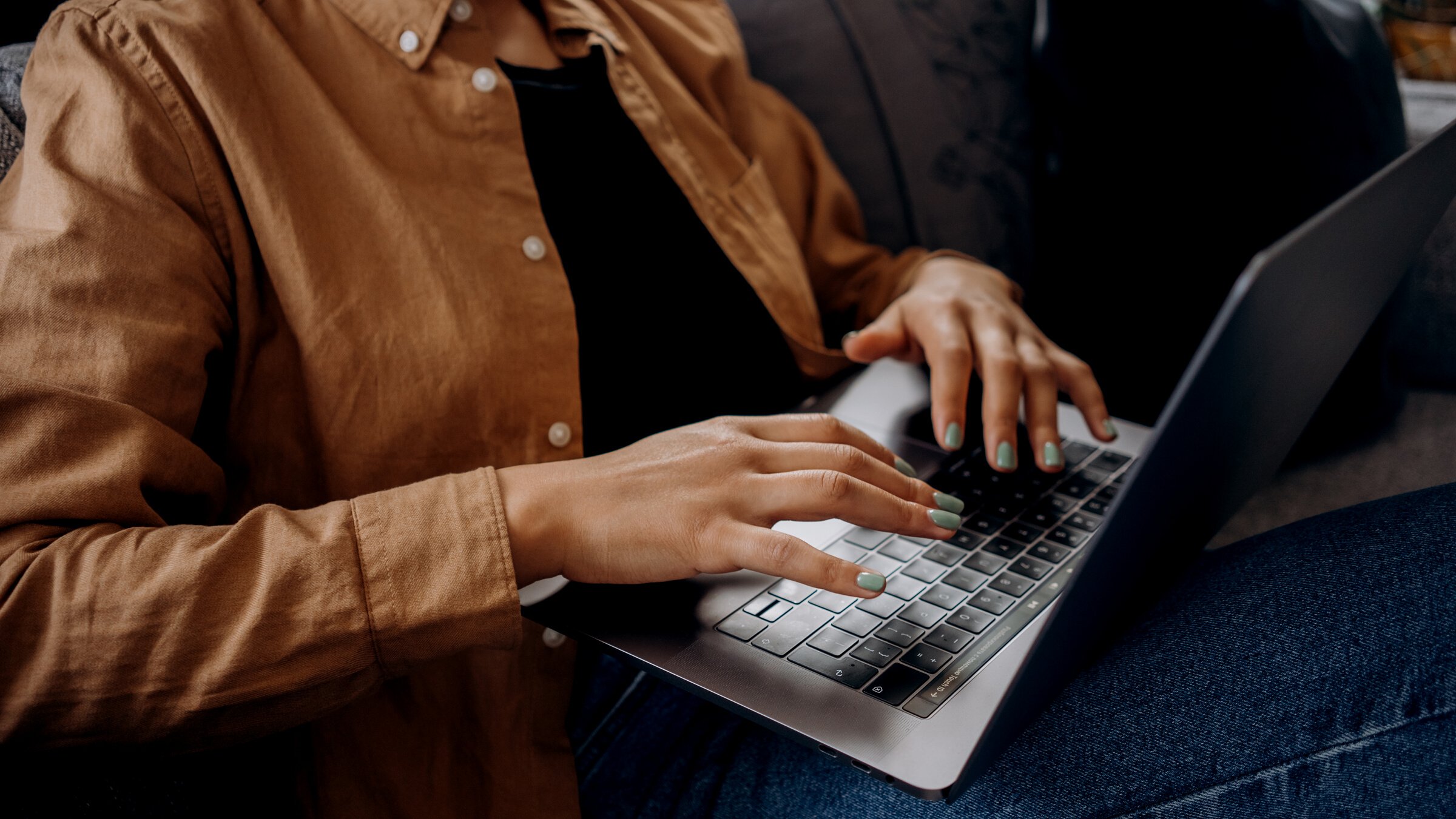 Person in Brown Button Up Shirt is Using a Macbook Pro